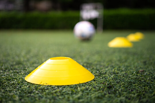 Obstacle cone for speed and moving training on artificial turf ground for football training. Sport equipment object photo. Selective focus at the front cone.