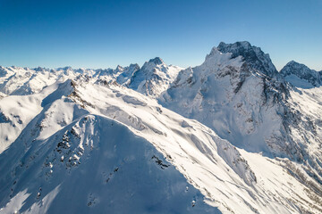 Fototapeta premium Snowy slope of Dombay mountains under clear sky 