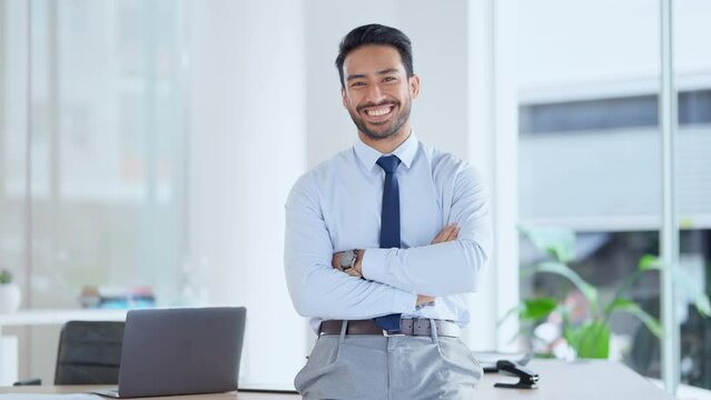 A confident successful male accountant is happy about his business achievement. Portrait of young financial advisor smiling with folded arms in his office. A proud bookkeeper at the workplace