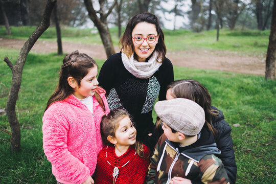 Same Sex Parents With Their Son And Daughters Laughing And Hugging In The Park. LGBT Homoparental Family