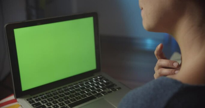 Woman having a video call on laptop and speaking from home. Green screen.
