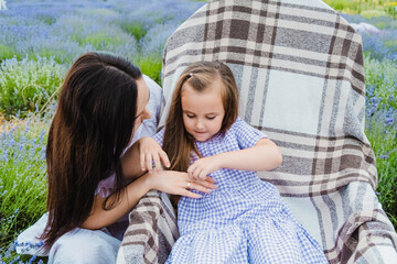 Sunday rest, flower field.A loving mother plays with his daughters, tickles, hugs and kisses.
