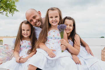 Cheerful bald dad hugs children.Children are having fun playing.Happy cheerful family in nature.Family the loving family