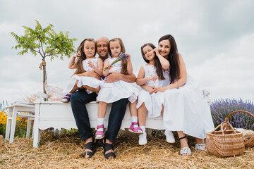 Naklejka premium Mother holds her daughter's hands. Nice family on a picnic in a lavender field. Cheerful mother and children are playing in a field of lavender flowers France.
