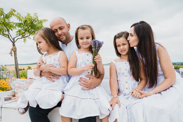 Portrait of a happy smiling family.Loving dad and mom hug and kiss their children. Children hold a bouquet of lavender in their hands.