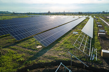 Aerial view of big electric power plant under construction with many rows of solar panels on metal...