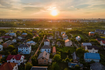 Naklejka premium Aerial view of residential houses in suburban rural area at sunset