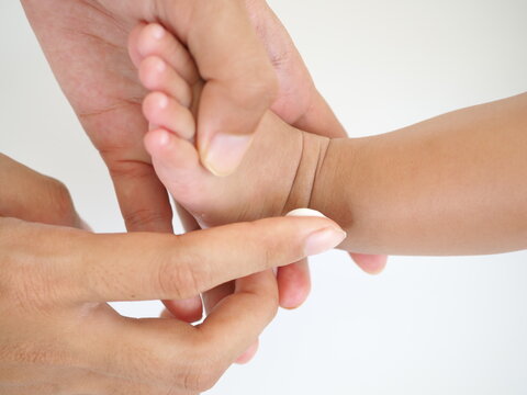 Mother hand holding infant leg, carefully applying medical ointment. Care about baby body. closeup photo, blurred.