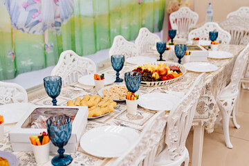 a large festive table with appetizers and glasses of blue glass.