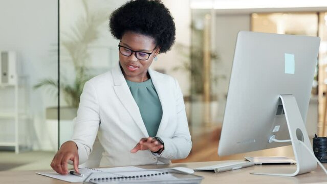 African female financial manager writing notes from her computer in her office. A black woman investment advisor working at her accounting firm. Accountant calculating company funds at the workplace