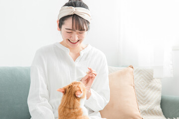 猫におやつをあげる日本人女性（餌）
