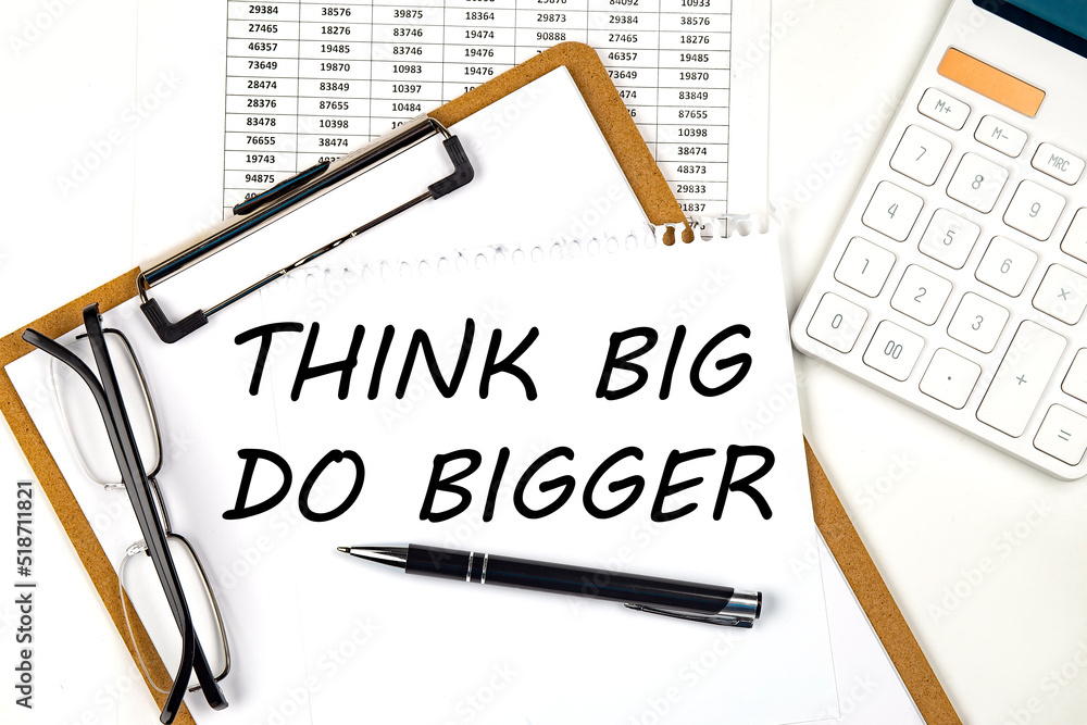 Poster text think big do bigger on the white paper on clipboard with chart and calculator