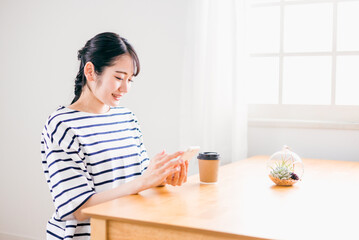 家のテーブルでスマホを使う日本人女性（アプリ・笑顔）
