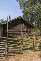 Obraz premium Old log barn house, wood fence and a sledge resting at the façade a sunny summer day in Stockholm