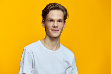 portrait of a smiling guy on a yellow background in a white T-shirt