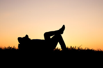 silhouette of resting man on grass on orange background