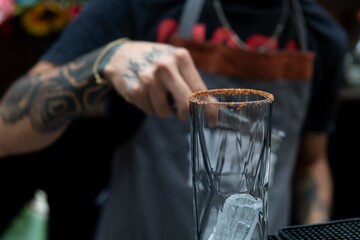 Glass cup with ice and frosty on top. Unrecognizable waiter seen from the chest preparing a drink in an empty glass. Waiter about to fill a glass in a restaurant.
