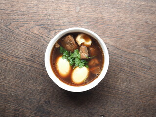 Top view bowl of braised PALO, Chinese five spice, pork and egg stew on wooden table