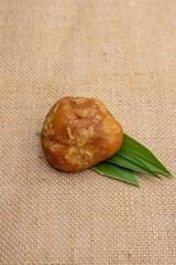 Closeup of Organic Palm Jaggery with Leaves Isolated on Burlap Fabric in Vertical Orientation