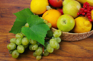 Grapes, apples, pears, lemons in a basket on the table.