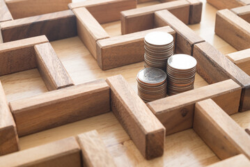 Stack coins in middle of wooden maze game background. Business and financial strategy, investment,...
