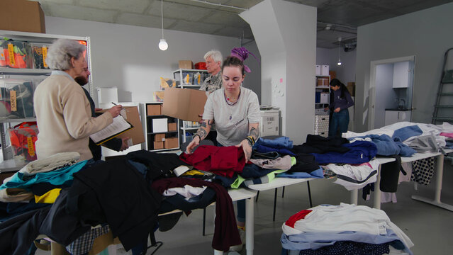 Woman sorting clothes for charity in volunteer center