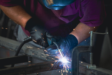 Industry worker welding iron pieces at work