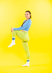 Fototapeta na wymiar girl in a sports top and leggings. athlete in golf. Sports girl doing exercises for the buttocks with a resistance band on a yellow background. Fitness woman exercising. yellow background