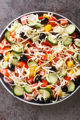 Serbian salad called sopska salata with vegetables and cheese closeup in the plate on the table. Vertical top view from above