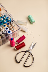 Tailor's table. Multicolored threads, beads and scissors on a beige background