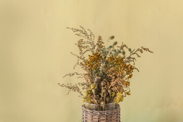 Bouquet of dry herbs and poppy heads on an ocher background