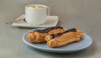 Close up of a chocolate eclairs and cup of espresso