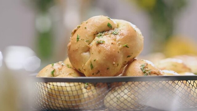 Chef puts garlic knots in the bowl.
