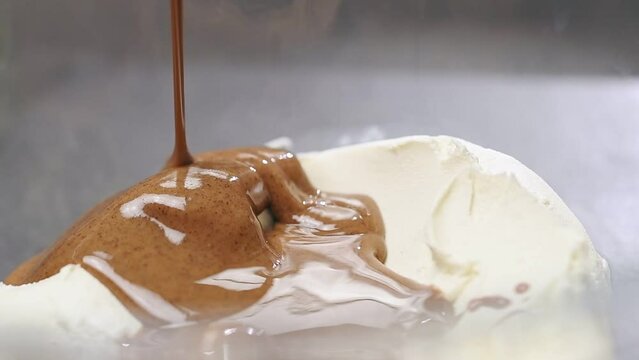 Ice cream making process. Pouring hazelnut butter into a glass bowl with mascarpone cheese.
