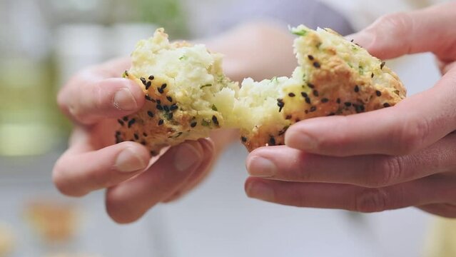 Female hands breaking freshly baked scone with cheese and green onion.
