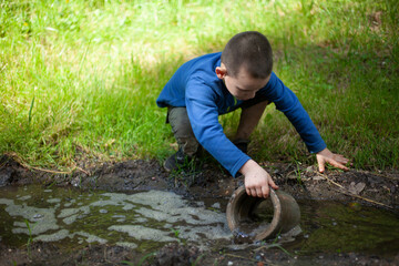 Child is holding dirty object. Little boy plays with concrete ring. Child found thing.