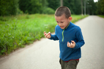 Child is angry. Boy threatens. Schoolboy swears in street.