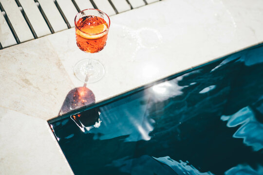 Spritz cocktails on poolside. Background of shining blue clear water in swimming pool.