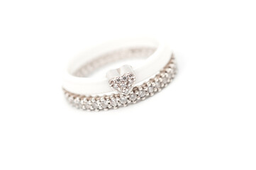 A white ceramic ring with a metal heart decorated with rhinestones and a silver ring with decorative stones.