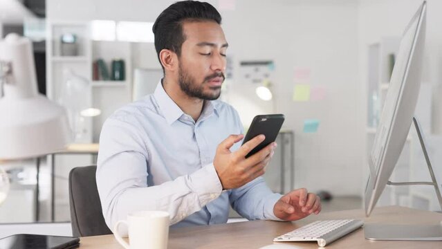 A young businessman copying data from his phone to a computer in his office. Successful entrepreneur using modern devices to download software or apps and create login details and passwords online