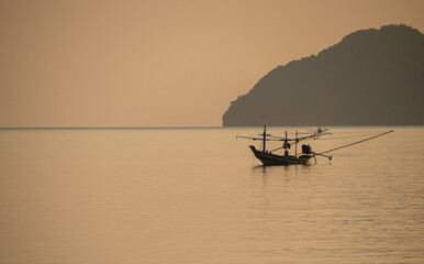 A small fishing boat moored in the middle of the sea during sunset.