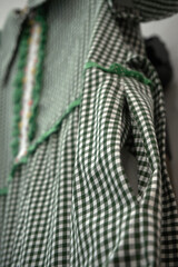 A green plaid dress with a decorative past openwork and patterns of paeto and bisser. Fashionable summer dress. Selective selective focus