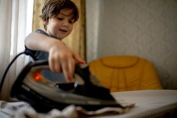 A five-year-old boy helps his parents around the house. A child ironing clothes, helping children around the house