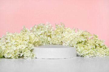 Round Podium with flowering hydrangea branches for product presentation. Abstract minimal geometrical form on pink background. One Showcase, white flowers, soft shadow. Scene, display. Front view