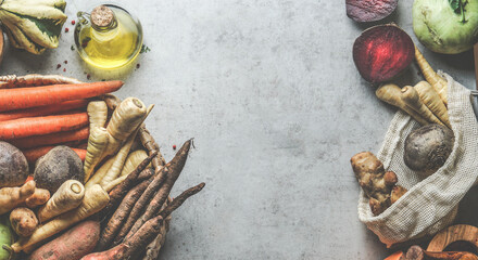 Food background frame with various organic root vegetables at grey concrete kitchen table:...