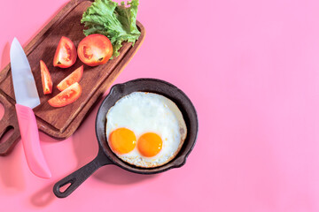Healthy breakfast food fried egg in skillet pan on pink table.