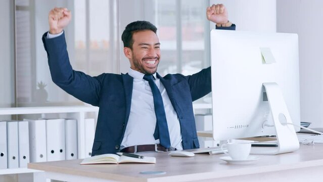 Happy trader and banker celebrating victory after reading good news about an exciting deal or bonus. Successful and excited business man cheering with joy while working on a computer in an office.
