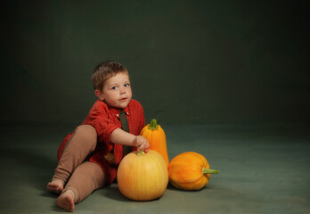 little boy with pumpkins on dark green background