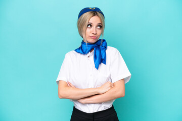 Airplane blonde stewardess woman isolated on blue background making doubts gesture while lifting the shoulders