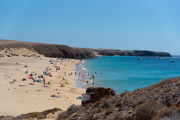 Fototapeta na wymiar Vista aérea de la playa mujeres en Lanzarote, Isla Canarias. Turistas tomando en el sol en la playa de canarias en un día de verano, Una cala salvaje con turistas.